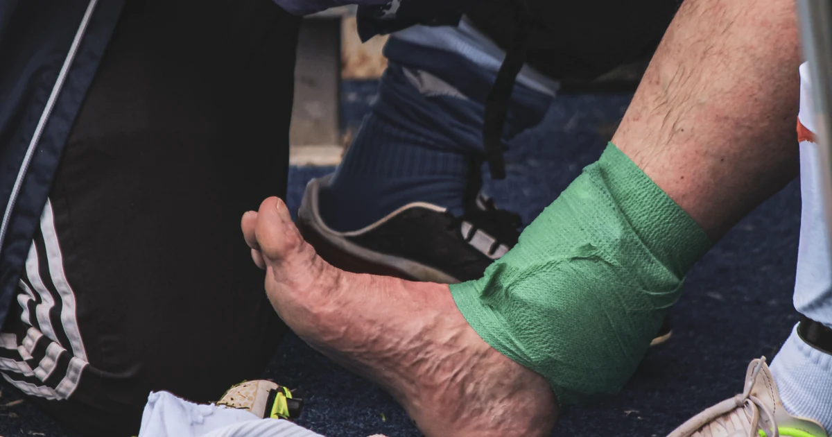 A teenage soccer player sits on the sideline while an athletic trainer checks a newly injured ankle.